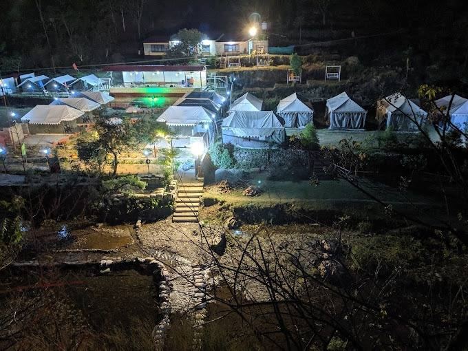 Camp lit up at night beside the river
